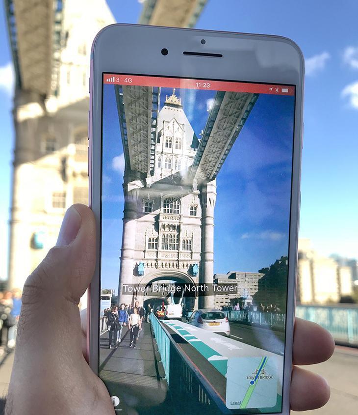 Person holding a smartphone displaying augmented reality navigation to the Tower Bridge North Tower.
